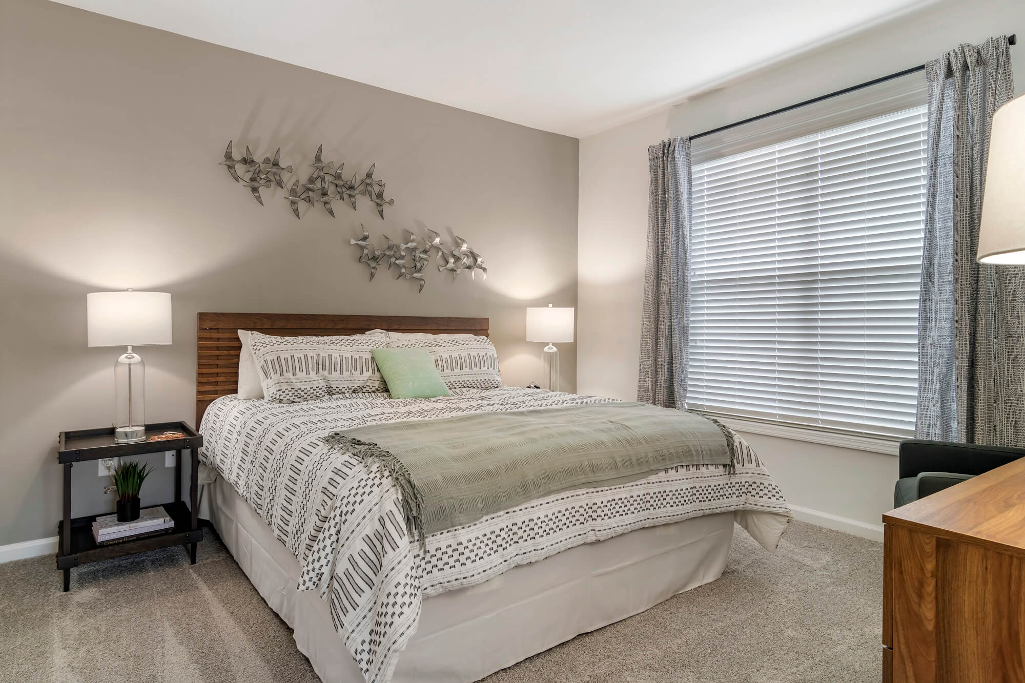 Model bedroom with large window, carpet, and gray accent wall