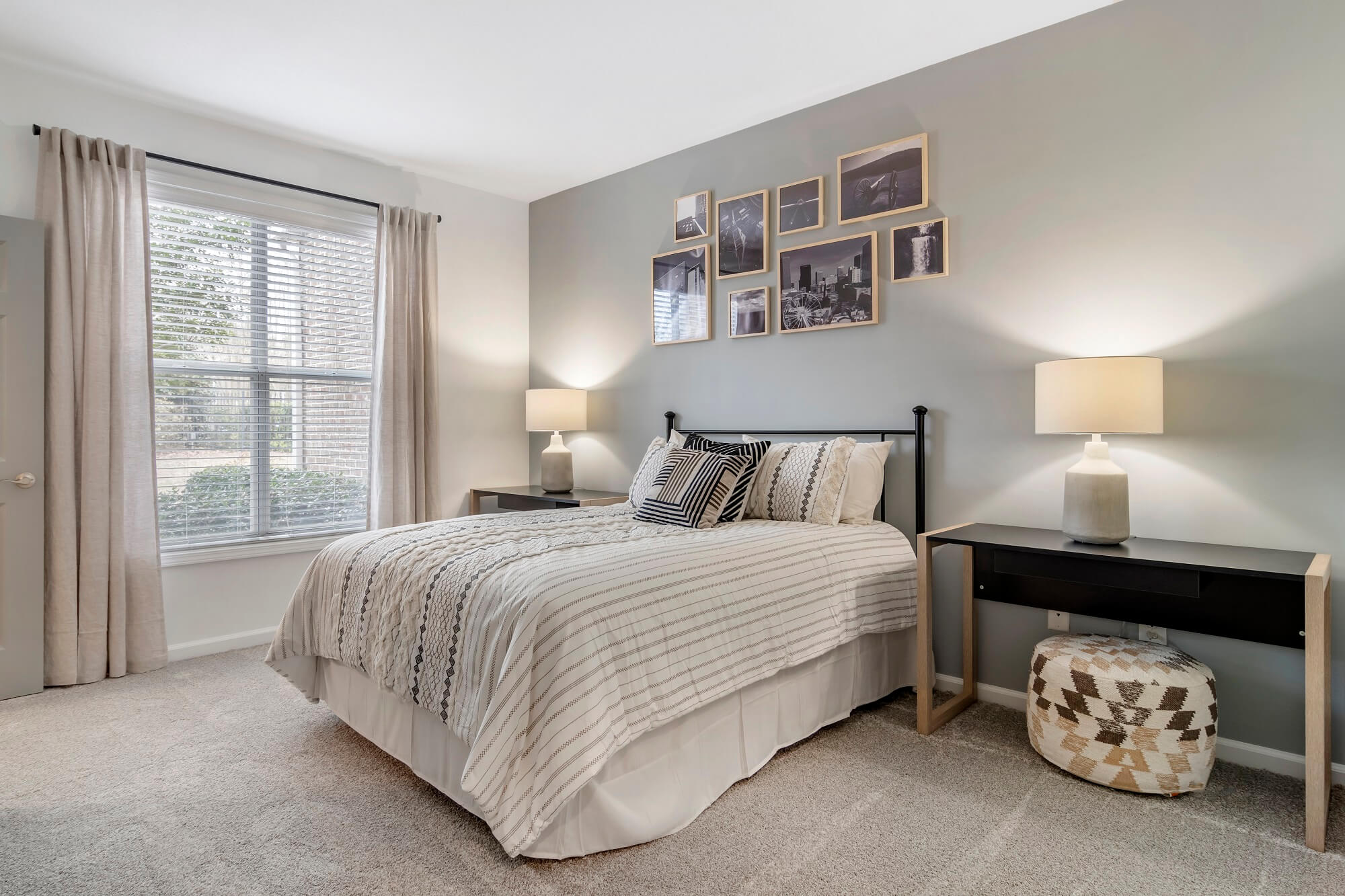 Model bedroom with large window, carpet, and gray accent wall