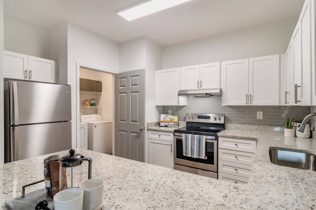 Model Kitchen with stainless steel appliances, granite counters, and tile backsplash