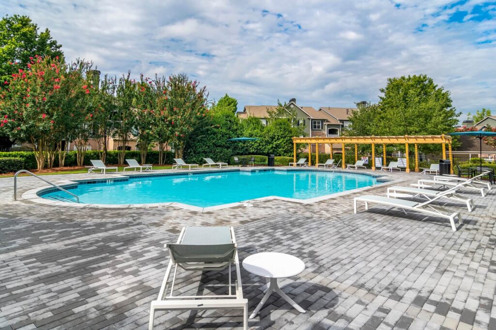 Pool with covered and uncovered deck seating surrounded by trees