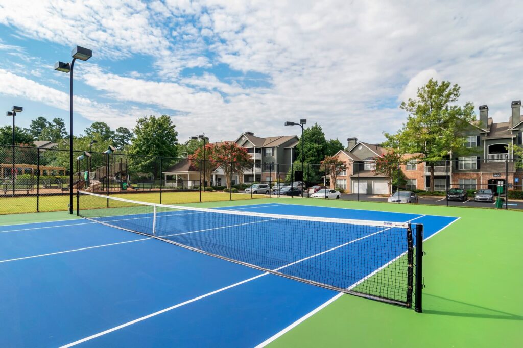 Fenced in tennis court with view of residential buildings